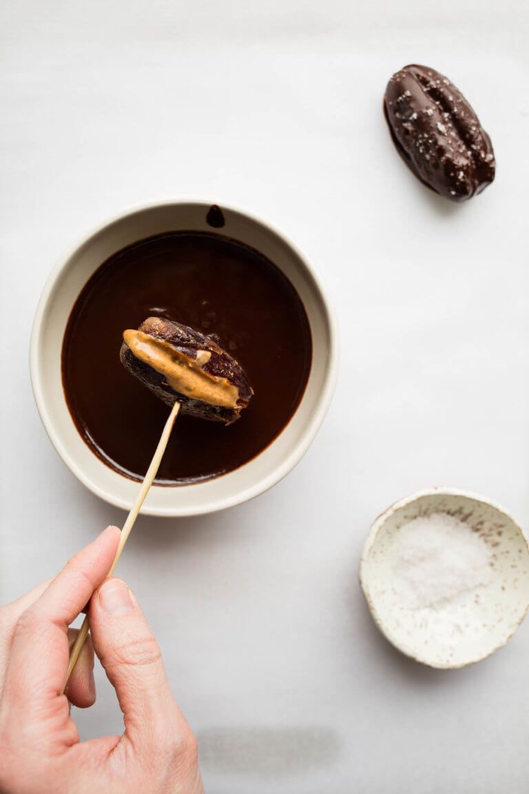 Date being dipped in chocolate